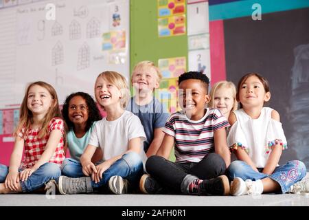 Group Of Elementary School Pupils Sitting On Floor In Classroom Stock Photo