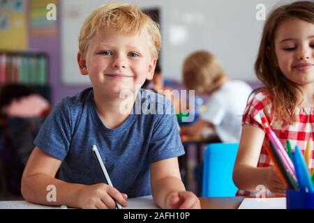 Portrait Of Male And Female Elementary School Pupils Working At Desk Stock Photo