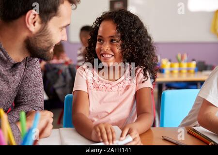 Elementary School Teacher Giving Female Pupil One To One Support In Classroom Stock Photo