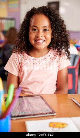 Portrait Of Female Pupil In Elementary School Drawing Using Digital Tablet In Classroom Stock Photo