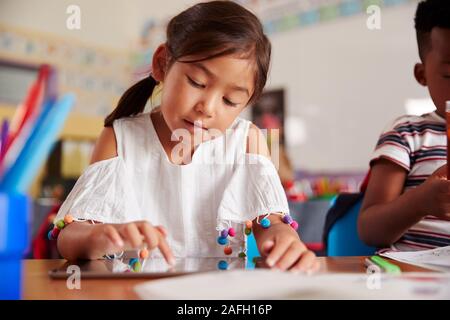 Female Pupil In Elementary School Drawing Using Digital Tablet In Classroom Stock Photo