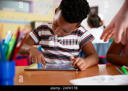 Male Pupil In Elementary School Drawing Using Digital Tablet In Classroom Stock Photo