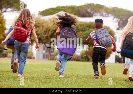 Rear View Of  Elementary School Pupils Running Across Field At Break Time Stock Photo