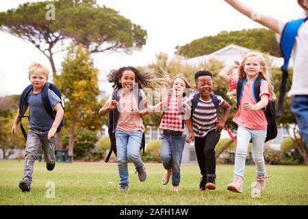 Excited Elementary School Pupils Running Across Field At Break Time Stock Photo