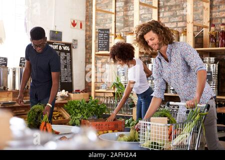 Shoppers Buying Fresh Fruit And Vegetables In Sustainable Plastic Free Grocery Store Stock Photo