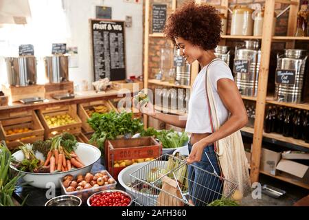 Woman Buying Fresh Fruit And Vegetables In Sustainable Plastic Free Grocery Store Stock Photo