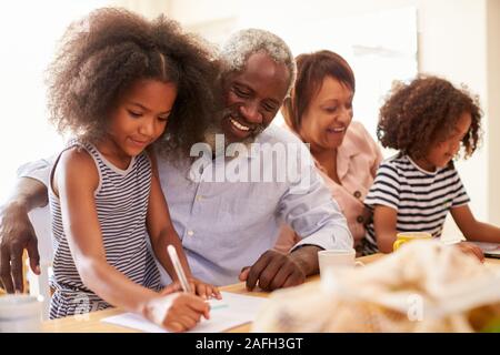Grandparents Sitting At Table With Grandchildren Playing Games Together Stock Photo