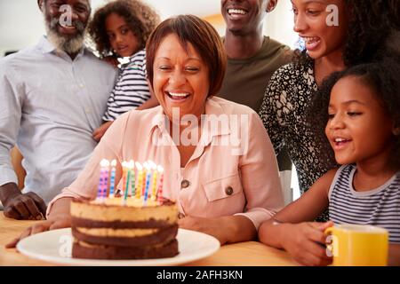 Multi-Generation Family Celebrating Grandmothers Birthday At Home With Cake And Candles Stock Photo