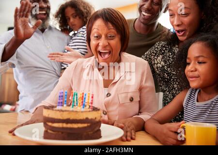 Multi-Generation Family Celebrating Grandmothers Birthday At Home With Cake And Candles Stock Photo