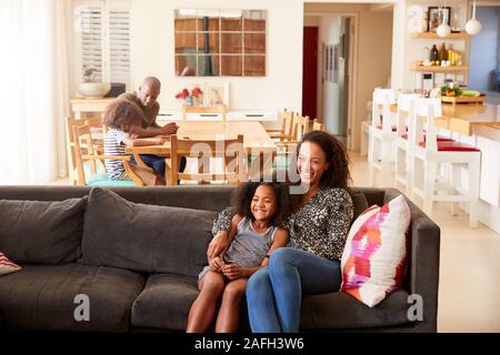 Mother And Daughter Sitting On Sofa At Home Watching Movie On TV Together Stock Photo