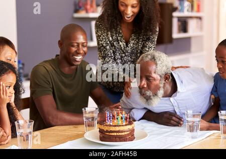 Multi-Generation Family Celebrating Grandfathers Birthday At Home With Cake And Candles Stock Photo