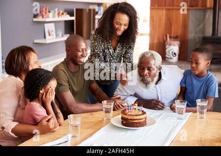 Multi-Generation Family Celebrating Grandfathers Birthday At Home With Cake And Candles Stock Photo