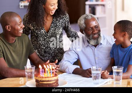 Multi-Generation Family Celebrating Grandfathers Birthday At Home With Cake And Candles Stock Photo