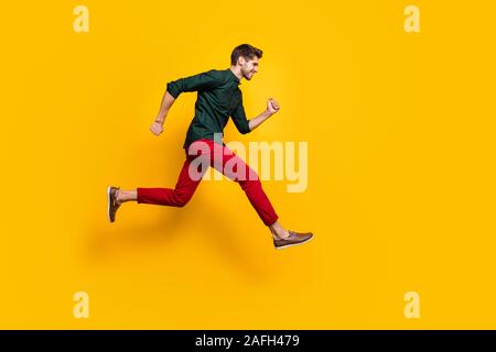 Full size profile side photo of positive cheerful guy jump run fast want hurry to sales discounts wear casual style clothes sneakers isolated over Stock Photo