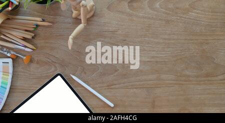 Top view of comfortable artist workplace with painting tools and tablet on wooden table Stock Photo