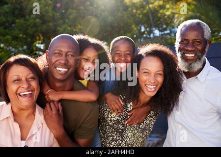 Outdoor Portrait Of Multi-Generation Family In Garden At Home Against Flaring Sun Stock Photo