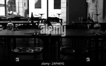 Greyscale shot of wine glasses placed upside down on a table in a restaurant Stock Photo