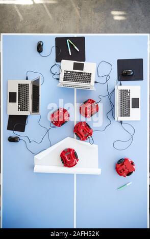 Overhead View Of Laptops And Robotic Vehicles On Table In School Computer Coding Class Stock Photo