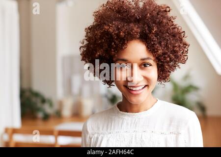 Portrait Of Smiling Young Woman In Loft Apartment Stock Photo
