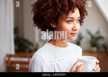 Young Woman Relaxing In Loft Apartment With Hot Drink Stock Photo