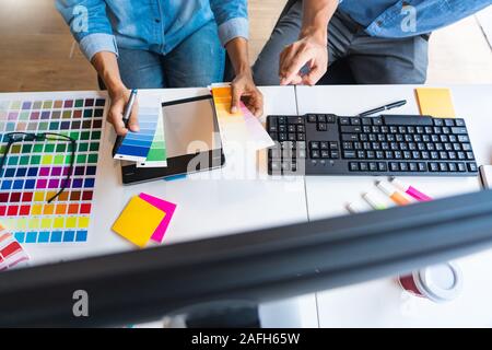 Professional Creative architect graphic desiner occupation choosing the Color pantone palette samples for project on office desktop computer. Stock Photo