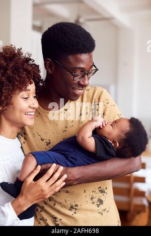 Loving Parents Holding Newborn Baby At Home In Loft Apartment Stock Photo