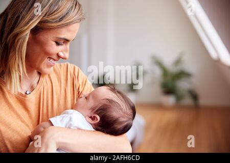 Loving Mother Holding Newborn Baby At Home In Loft Apartment Stock Photo