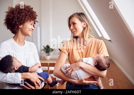 Two Mothers Meeting Holding Newborn Babies At Home In Loft Apartment Stock Photo