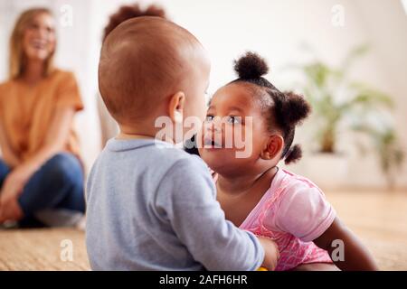 Two Mothers Meeting For Play Date With Babies At Home In Loft Apartment Stock Photo