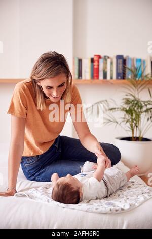 Loving Mother With Newborn Baby Lying On Bed At Home In Loft Apartment Stock Photo