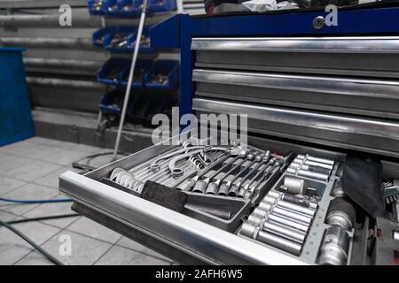 A set of tools from wrenches and heads for unscrewing nuts and bolts in a special cabinet or blue workbench for repair in a car service or at a factor Stock Photo