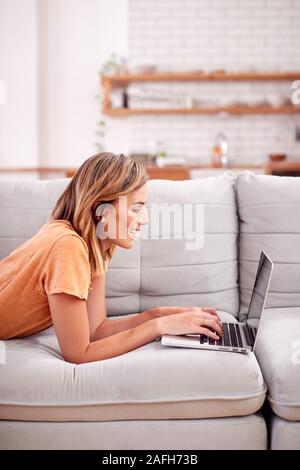 Woman Relaxing Lying On Sofa At Home Using Laptop Computer Stock Photo