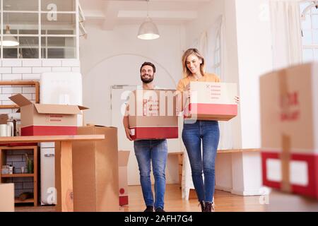 Smiling Couple Carrying Boxes Into New Home On Moving Day Stock Photo