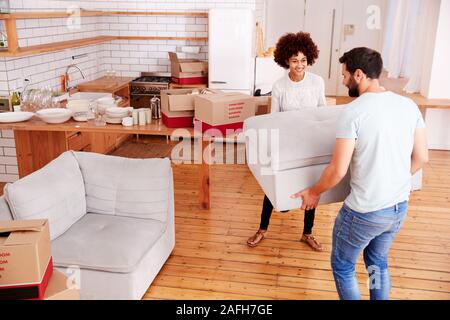 Smiling Couple Carrying Furniture Into New Home On Moving Day Stock Photo