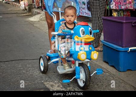 Child riding a cartoon pedal  bike with stabilizers attached. Stock Photo