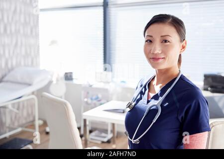 Portrait Of Smiling Female Doctor With Stethoscope Standing By Desk In Office Stock Photo