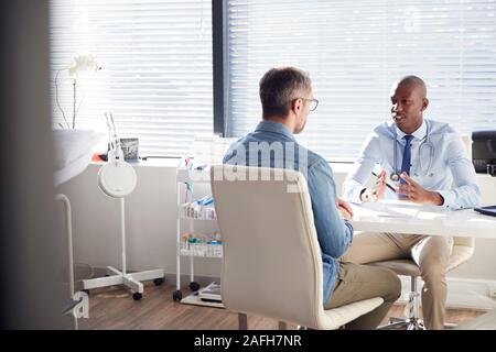 Mature Male Patient In Consultation With Doctor In Office Stock Photo