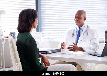 Female Patient In Consultation With Doctor Sitting At Desk In Office Stock Photo