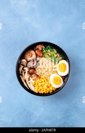 Ramen noodle soup. Soba with eggs, shiitake and enoki mushrooms, sweetcorn and scallions, shot from above with copy space Stock Photo