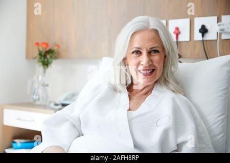 Portrait Of Mature Female Patient Lying In Hospital Bed Smiling At Camera Stock Photo