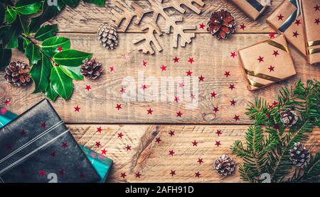 Flat lay picture christmas holiday concept with gifts, fir tree branch, wooden snow star and pine cones. Copy space in the center. Stock Photo