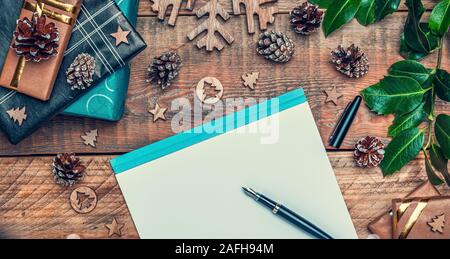 Christmas letter to Santa Claus concept. Flat lay composition with writing paper, pen, cone pines, wrapped gifts and xmas decoration.