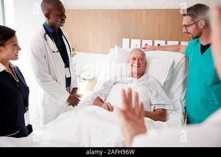 Medical Team On Rounds Meeting Around Bed Of Senior Male Patient Stock Photo