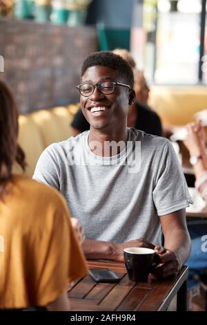 Couple Sitting At Table In Busy Coffee Shop Talking Stock Photo