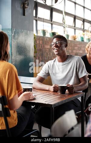 Couple Sitting At Table In Busy Coffee Shop Talking Stock Photo
