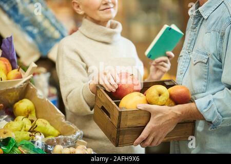 Cropped portrait of smiling senior couple choosing fruits while enjoying grocery shopping at farmers market, copy space Stock Photo