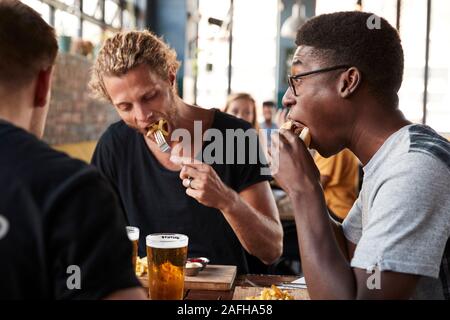 Three Young Male Friends Meeting For Drinks In Restaurant Stock Photo