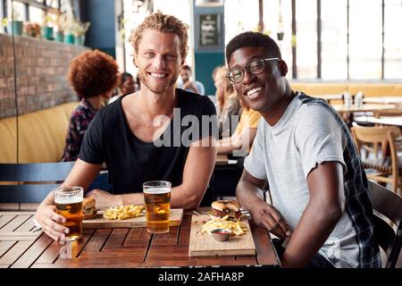 Portrait Of Two Young Male Friends Meeting For Drinks In Restaurant Stock Photo