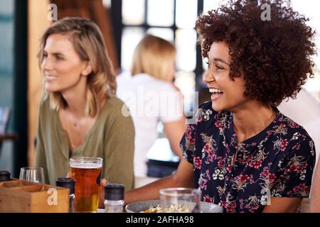 Two Young Female Friends Meeting For Drinks And Food In Restaurant Stock Photo