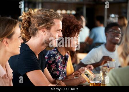 Group Of Young Friends Meeting For Drinks And Food In Restaurant Stock Photo